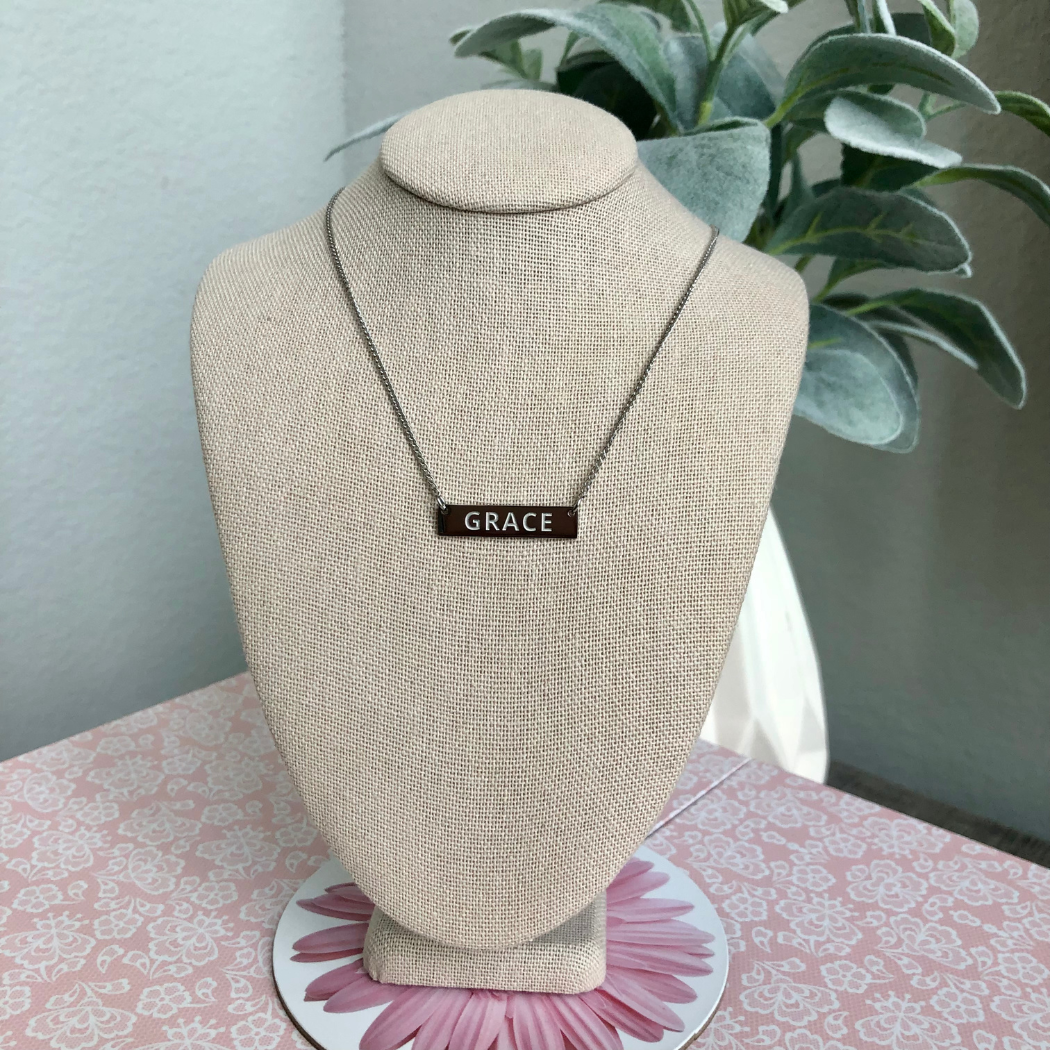 Silver necklace engraved with the word Grace.