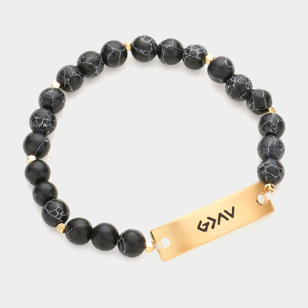 An inspirational bracelet with a metal bar and natural stones, showcasing the empowering message "God is Greater Than the Highs and Lows."
